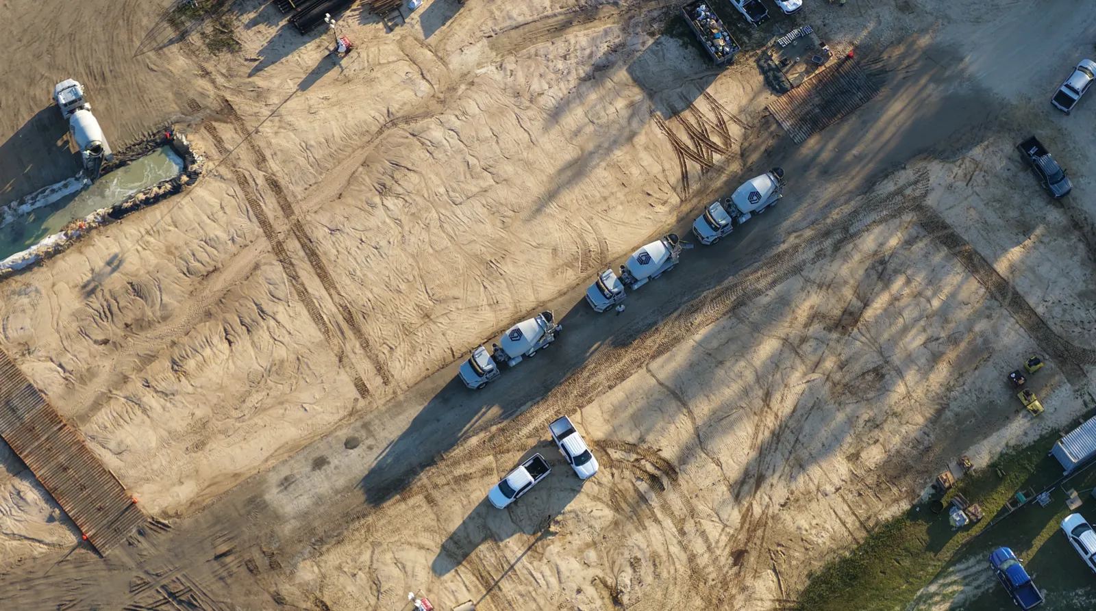 Top-down drone shot of concrete mixer trucks lined up on a commercial job site